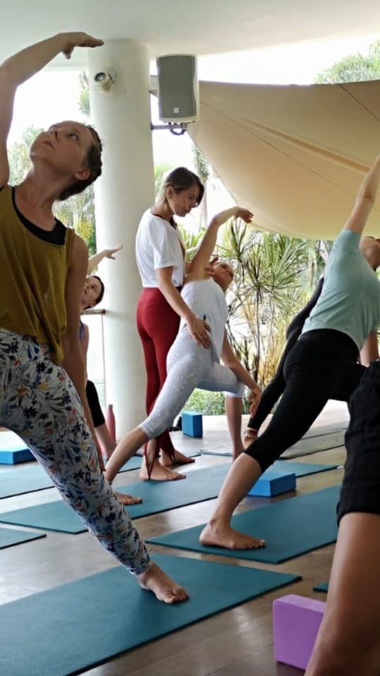 Yogalehrerin Dela Marlen korrigiert die Haltung von Yogaschülern
